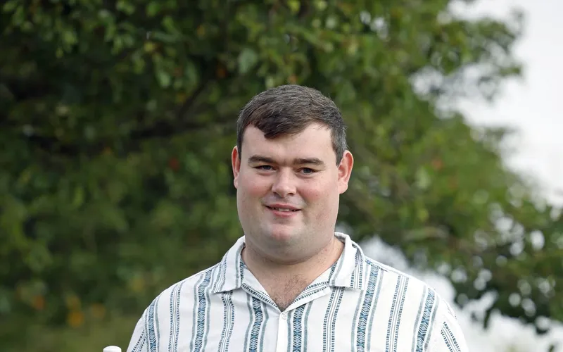 Brandon Hulcoop, in a striped shirt, photographed outdoors.