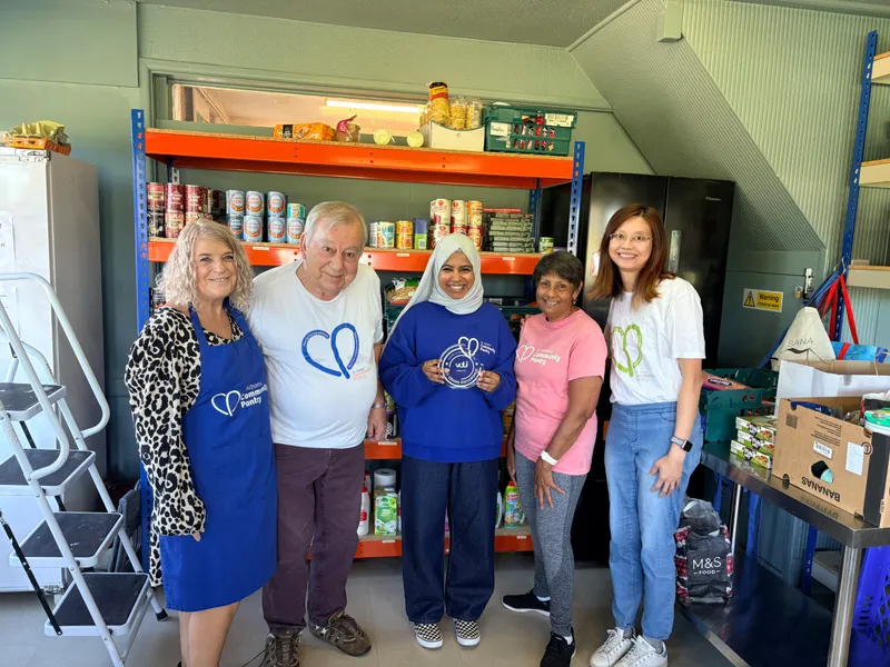 Raihaanah Ahmed and volunteers at St Albans Community Pantry, in front of shelves of food.